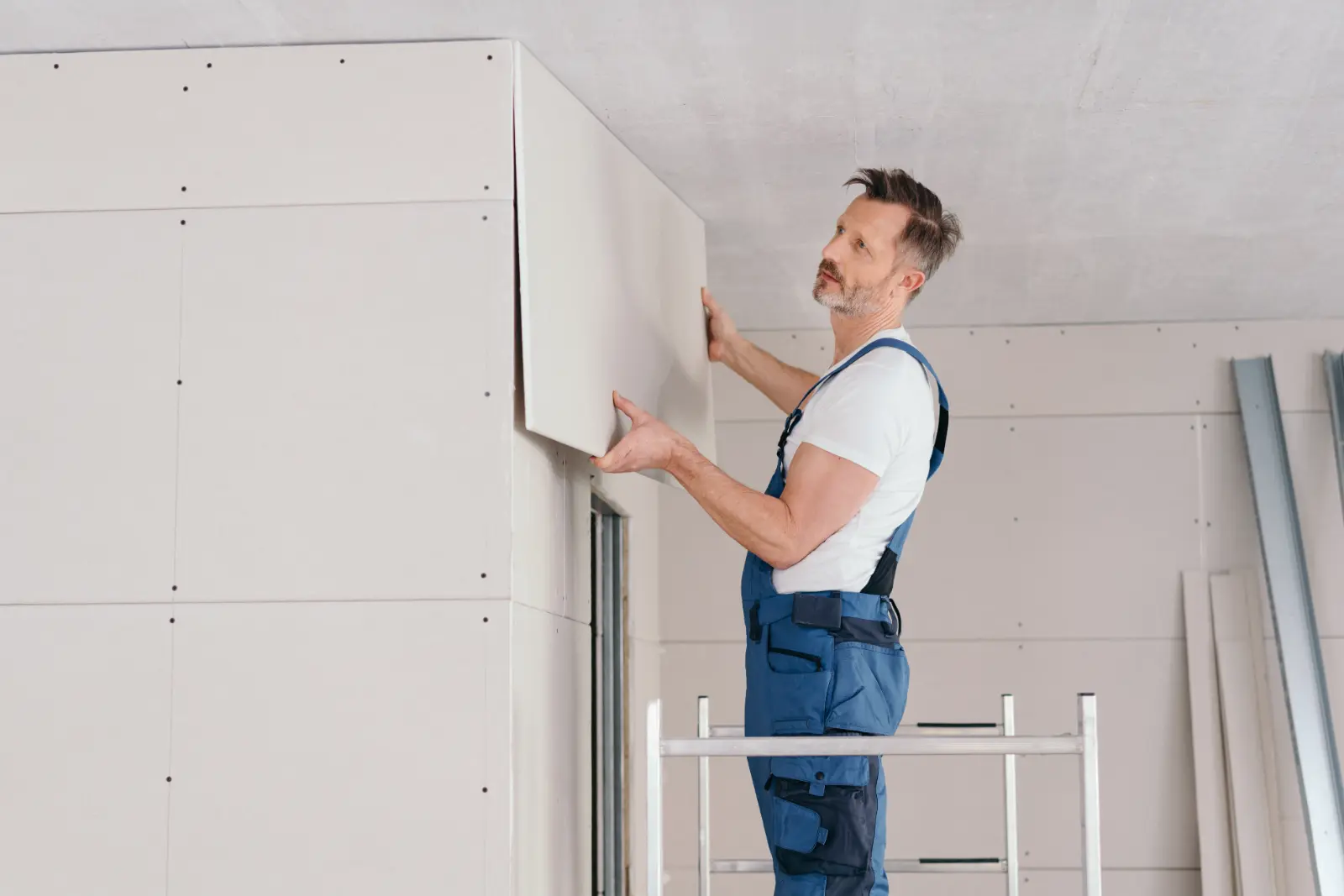 Ceiling Drywall Installation. Builder or handyman fitting wall cladding