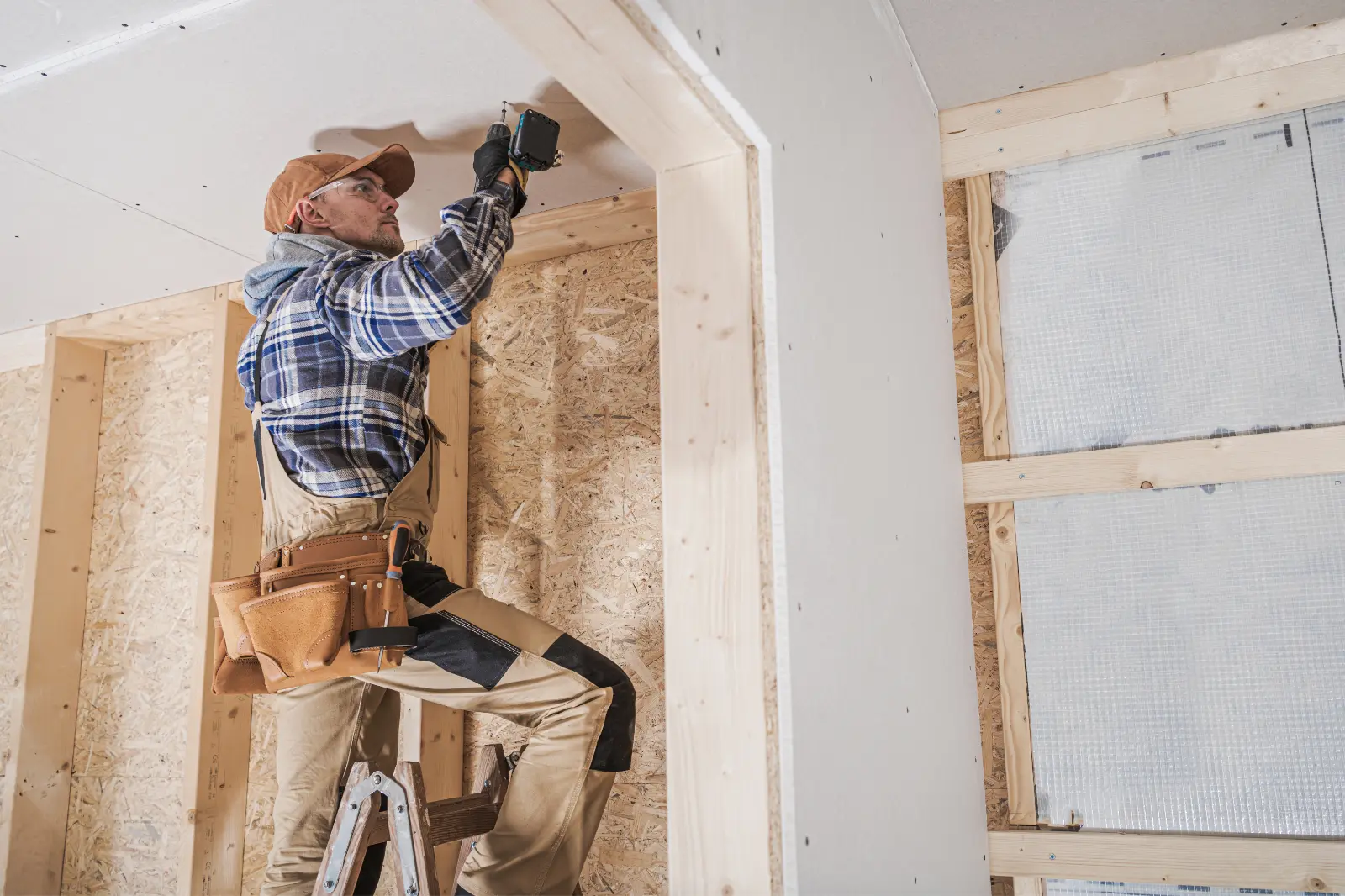 Drywall Installation. Builder with plasterboard in new building interior