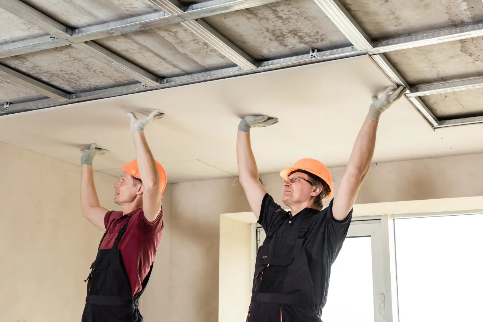 Drywall Installation Tactics. Workers are attaching plasterboardto the ceiling