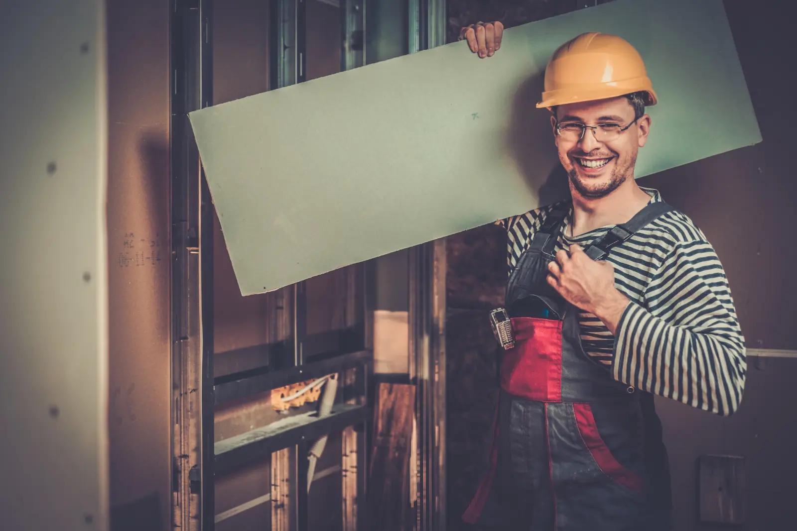 Builder with plasterboard in new building interior (2)