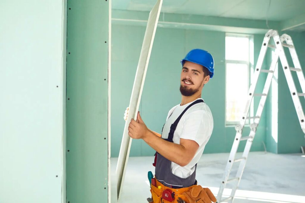 Plasterboard Walls. Worker builder installs plasterboard drywall at a construction